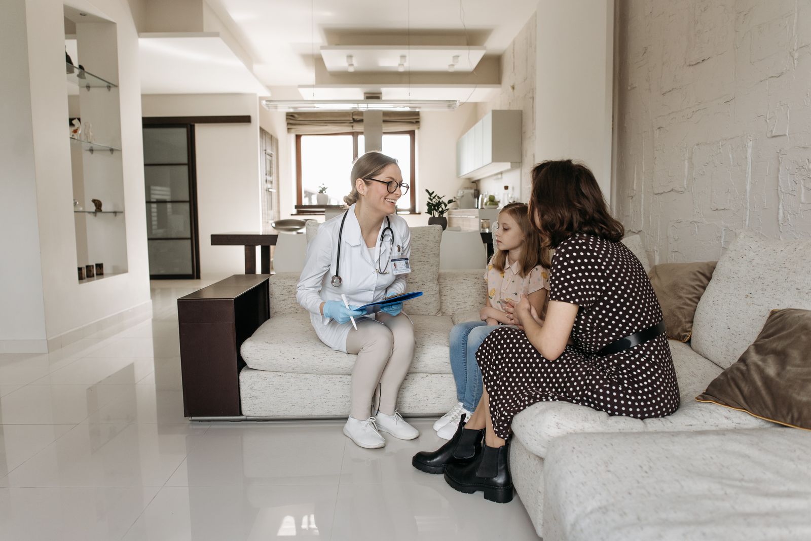 A doctor speaking with a mother and child during a home visit